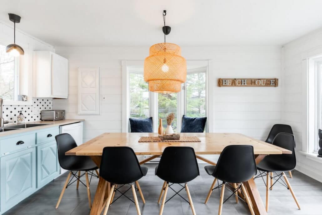 Coin repas d'un chalet avec chaises noires et cuisine blanche
