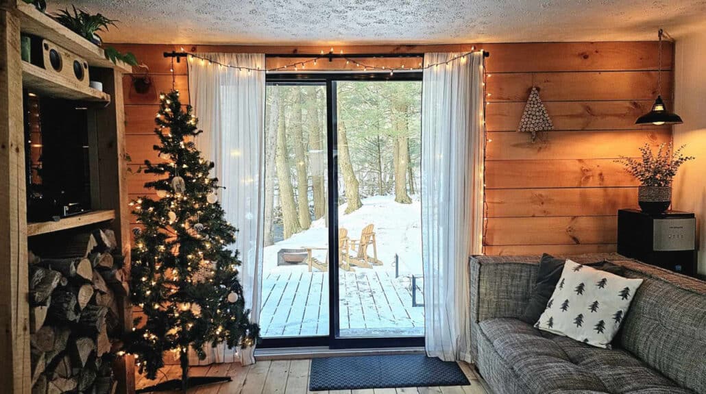 Intérieur d'un chalet avec sapin de Noël et canapé près des portes-fenêtres