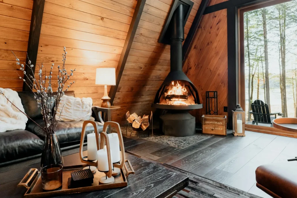 Salon de chalet mis en scène en style hygge, foyer allumé et coussins texturés
